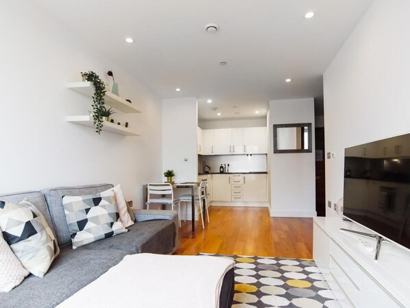 A modern apartment with a grey sofa, a dining area, and a kitchen. - The Most Central Apartment in Cardiff - Pass the Keys (Cardiff)