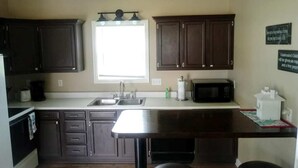 A kitchen with dark wooden cabinets, a stainless steel sink, a microwave, and a small island with stools. - Downtown, close to everything, family friendly, newly renovated. (South Haven)