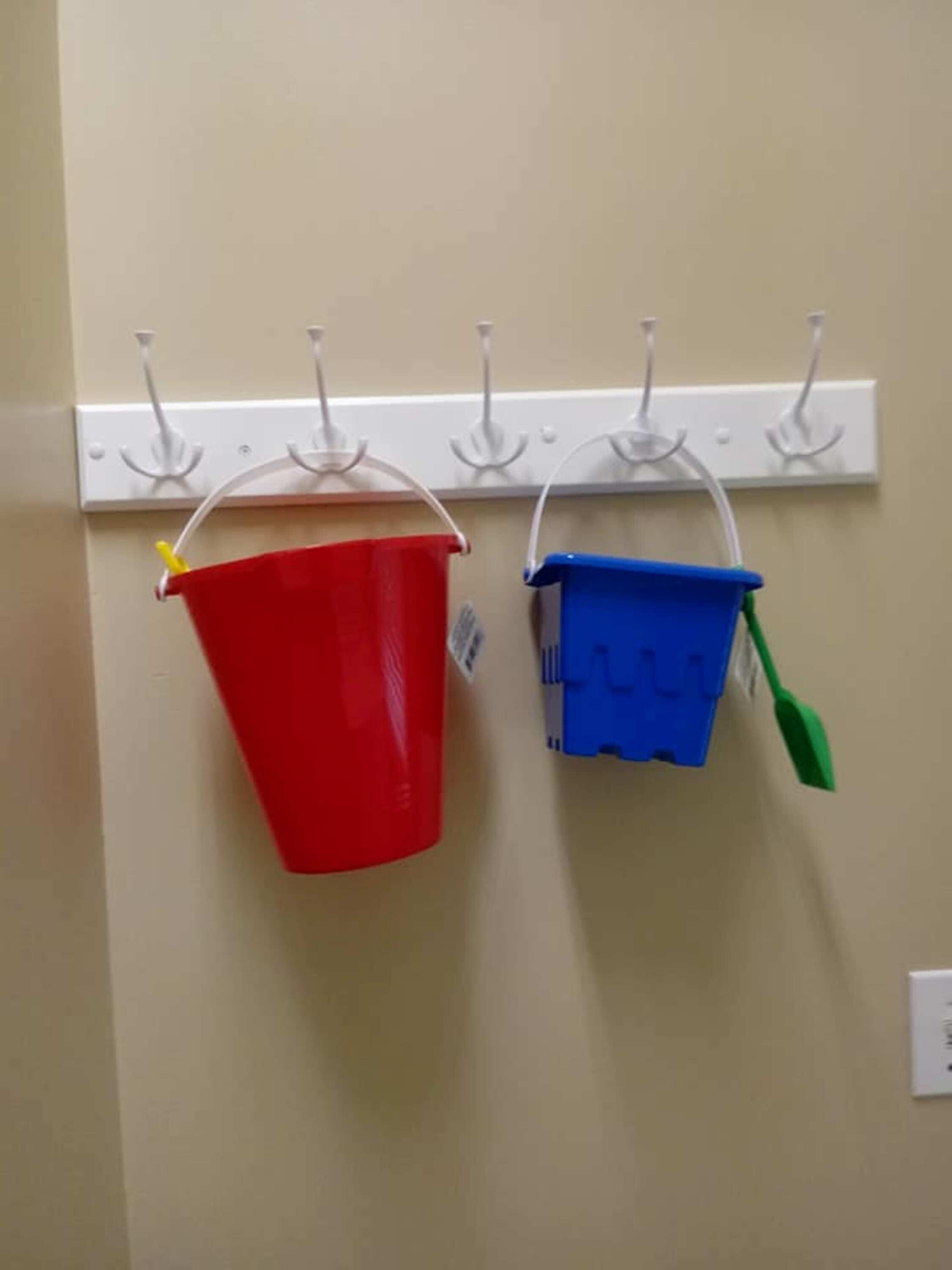 Dos cubos, uno rojo y uno azul, colgados en un perchero de pared.