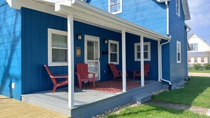 A blue house with a porch, red chairs, and a small table. - Downtown, close to everything, family friendly, newly renovated. (South Haven)