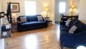 A living room with a dark blue sofa, a coffee table, a lamp, and a television. - Downtown, close to everything, family friendly, newly renovated. (South Haven)