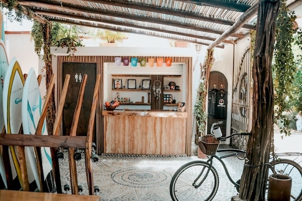 A beachside cafe with surfboards, a wooden counter, and a bicycle. - Casa de Olas Boutique Hotel (Puerto Escondido)