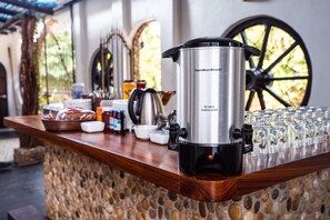 A stainless steel Hamilton Beach hot surface coffee pot on a wooden counter with various breakfast items and glassware. - Casa de Olas Boutique Hotel (Puerto Escondido)