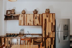 Una cocina con armarios de madera, un refrigerador de acero inoxidable y un lavamanos.