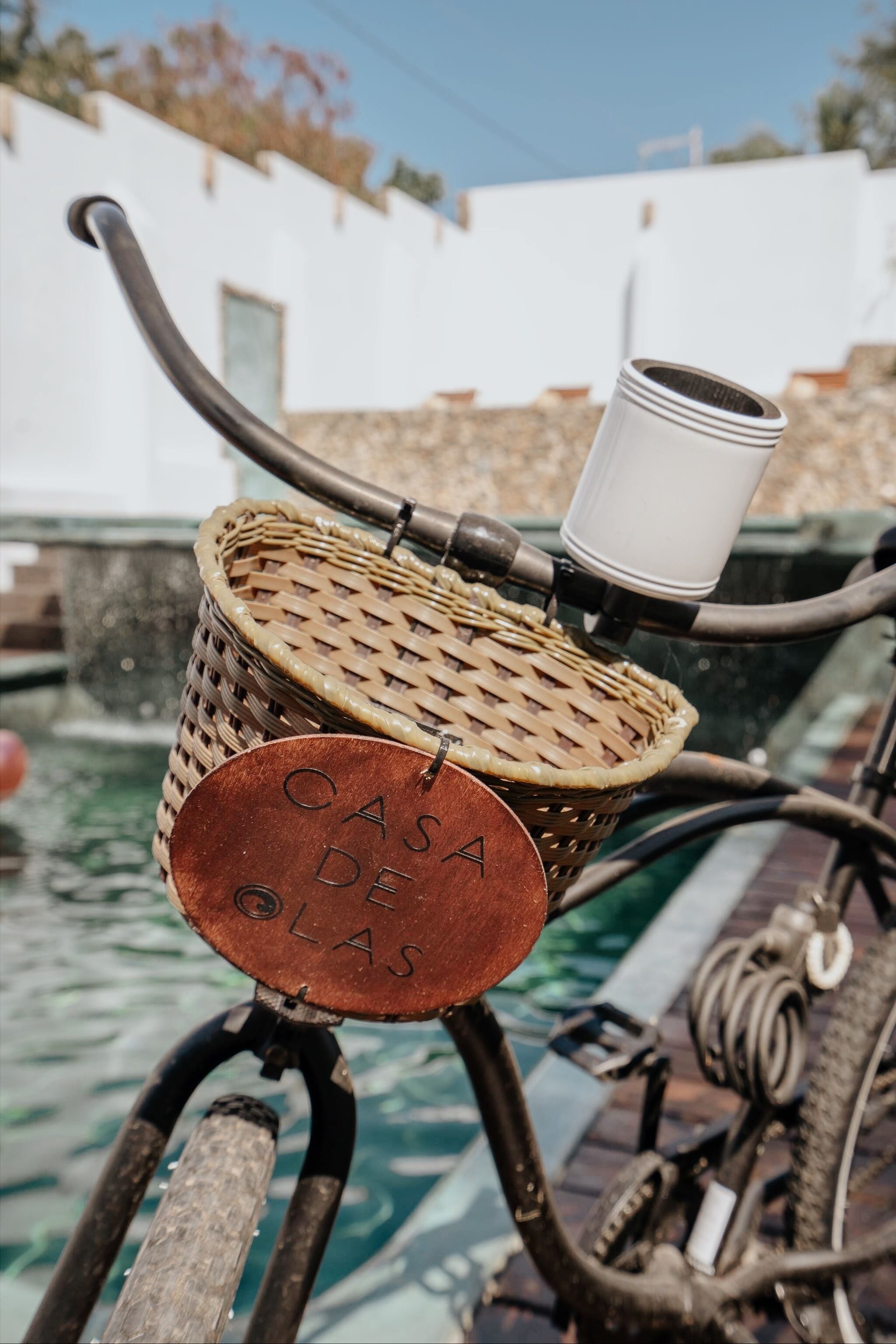 Una cesta de mimbre con una taza blanca sobre una bicicleta.