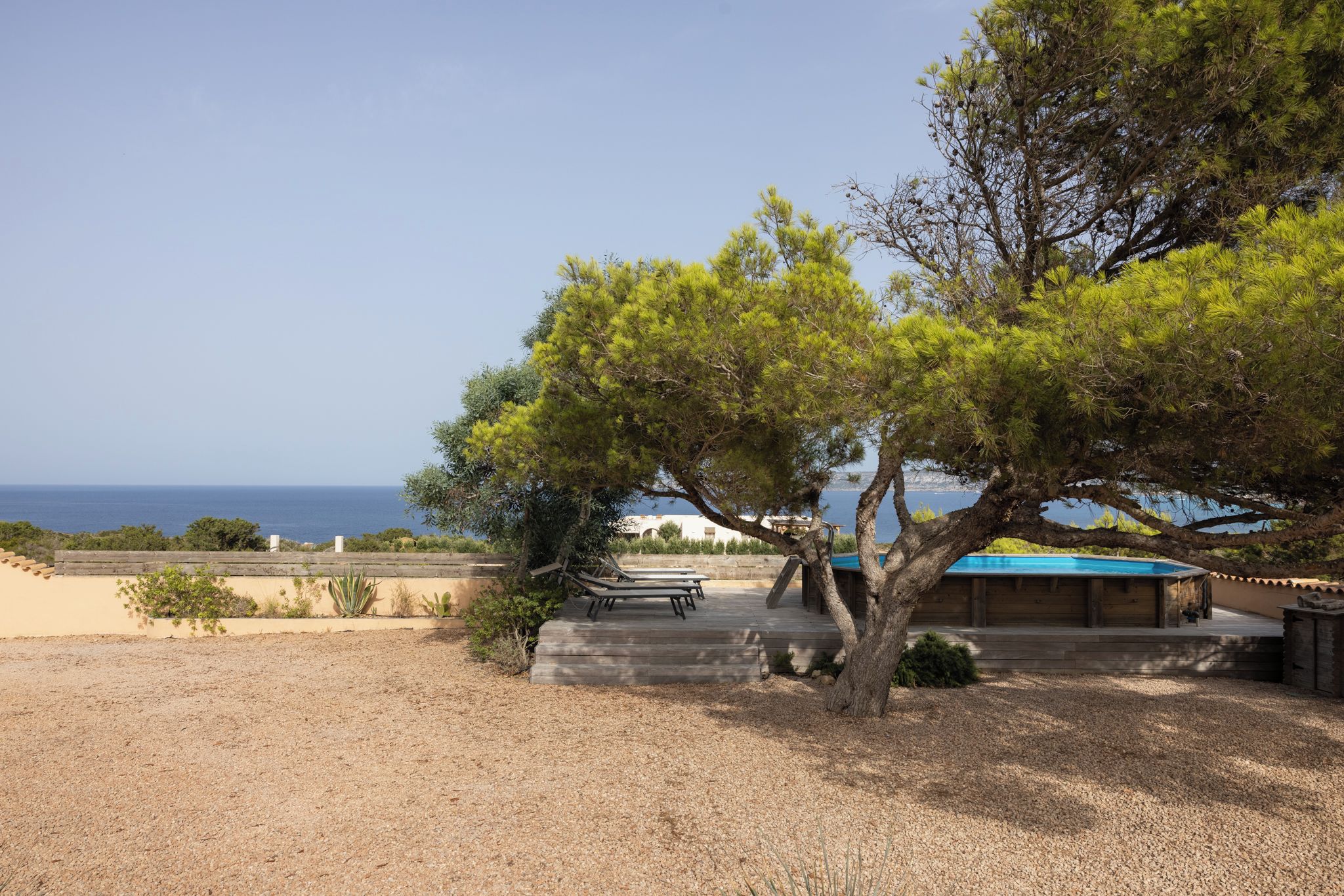 Area piscina con vista mare, un pontile in legno e una sedia a sdraio.