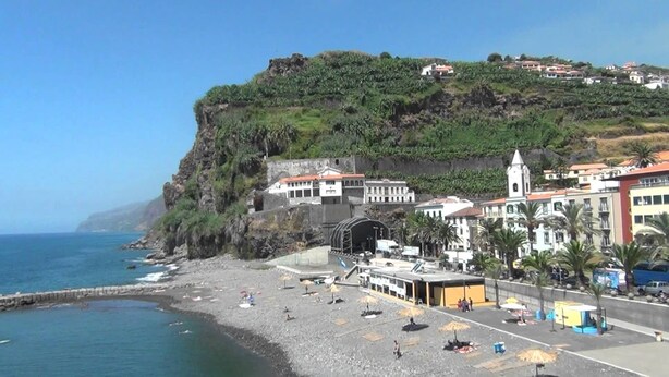 Un pueblo costero con playa, edificios y un acantilado.