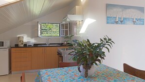 Una cocina con armarios de madera, microondas, cafetera y ventana con vista a follaje.