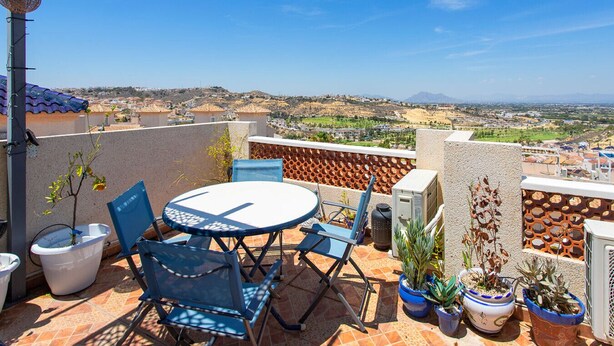A terrace with a round table and chairs, potted plants, and a view of a town and hills. - CH Grazalema La Marquesa Golf (Ciudad Quesada) (Ciudad Quesada)