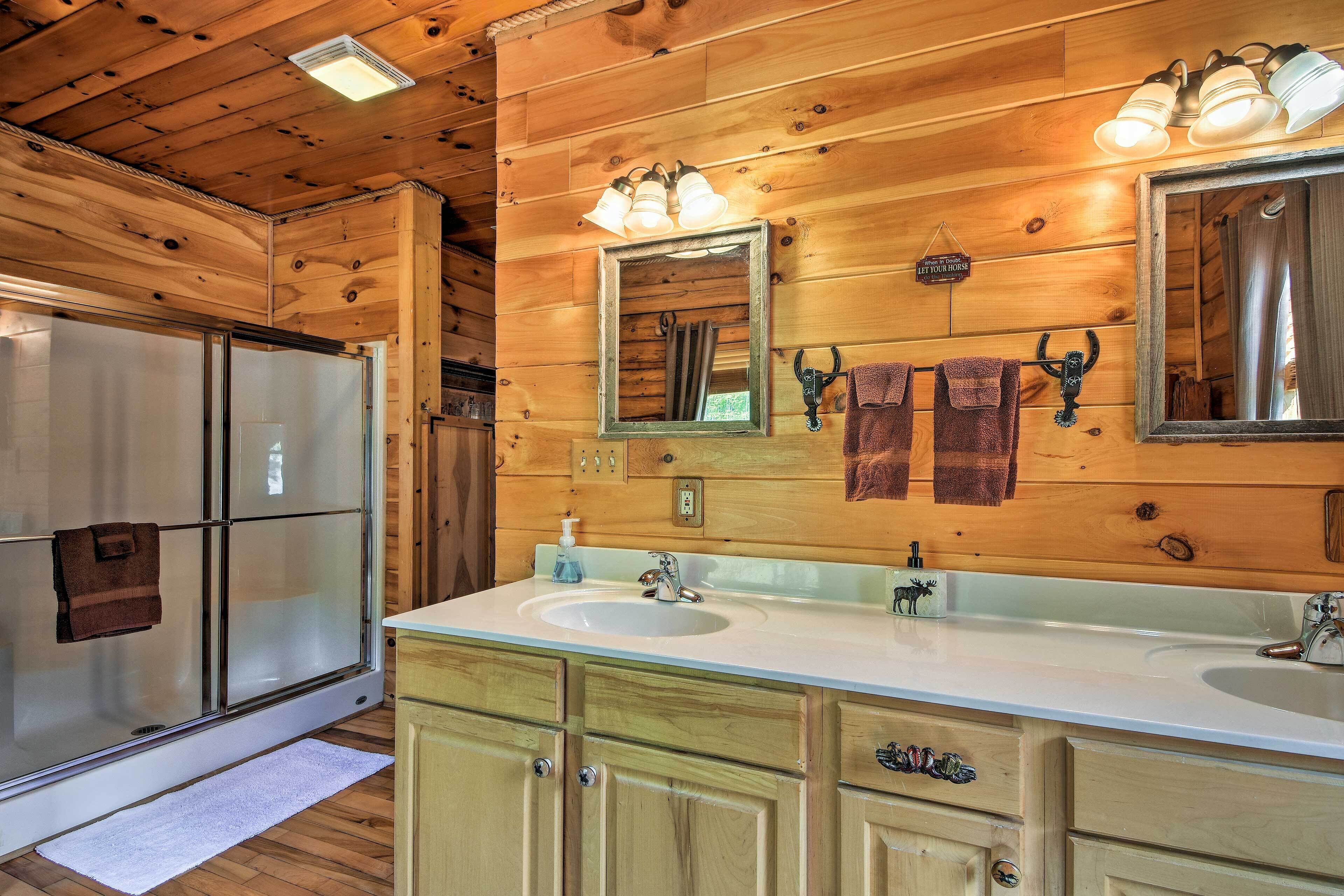 A wooden cabin bathroom with a double sink, a mirror, and a shower.