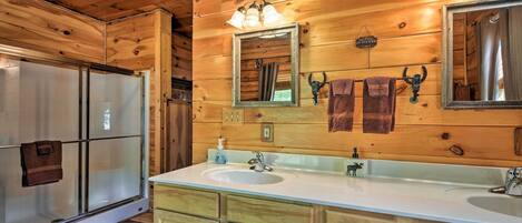 A wooden cabin bathroom with a double sink, a mirror, and a shower.