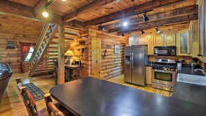 A log cabin interior with a kitchen, dining area, and a staircase. - Cozy Trenton Cabin w/ Spa ~ 15 Mi to Lookout Mtn! (Trenton)