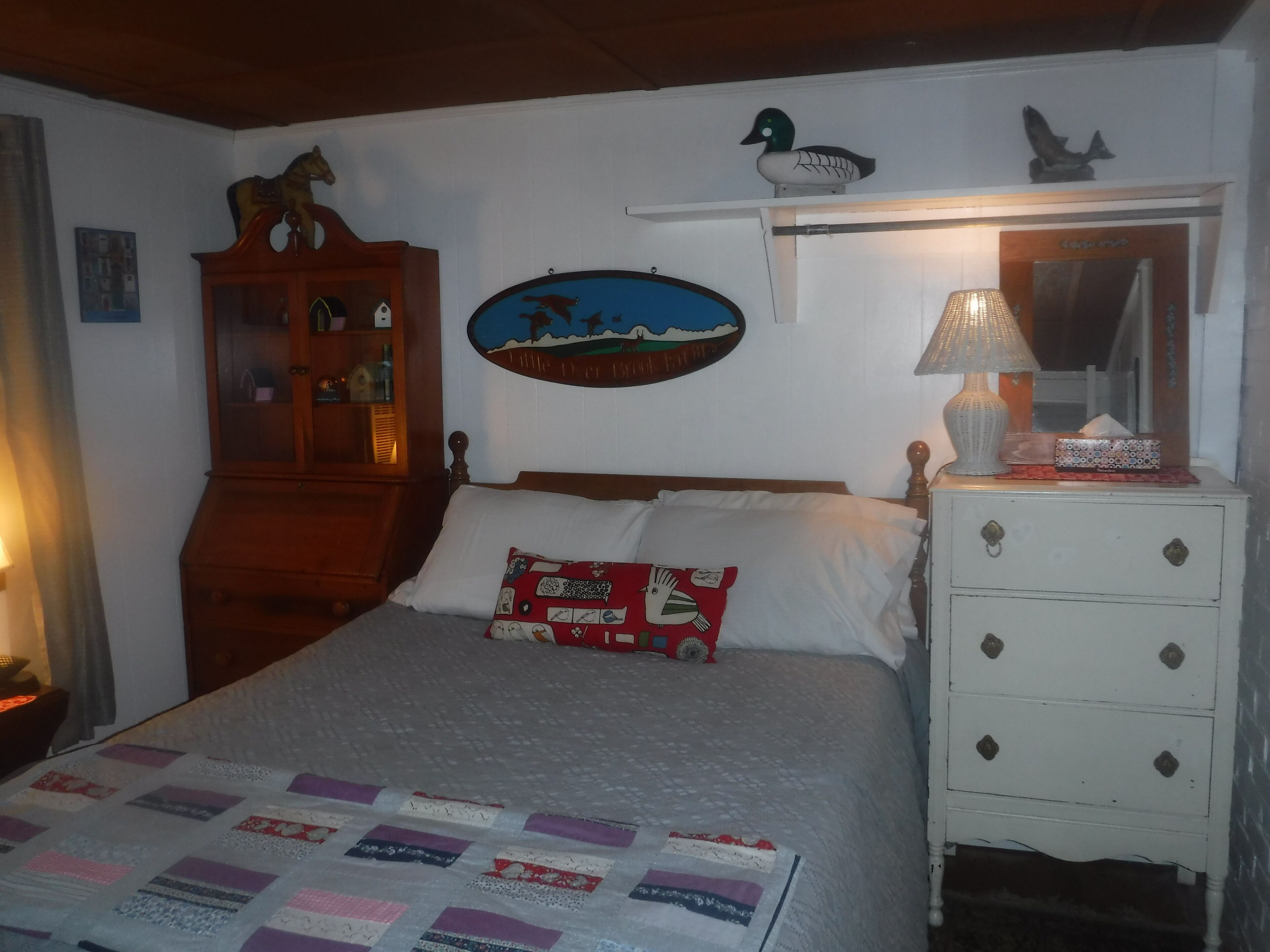 A bedroom with a bed, a dresser, a lamp, and a wall clock.