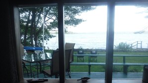 A room with a large window overlooking a body of water, a table with chairs, and a view of the outdoors. - WATERSEDGE  GREAT VIEWS (Jefferson)