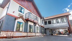 A multi-story building with a "BASECAMP LODGE" sign, stone foundation, and a red roof. - Basecamp Lodge I Double Queen Room (Canmore)