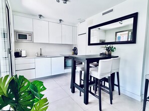 Uma cozinha moderna com armários brancos, micro-ondas e área de jantar com mesa e cadeiras.