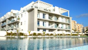 A modern multi-story hotel with balconies, a swimming pool, and a clear blue sky. - Stylish apartment with sea views (Torrox)