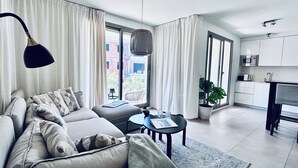 A modern living room with a sofa, a coffee table, and a dining area with a kitchen. - Stylish apartment with sea views (Torrox)