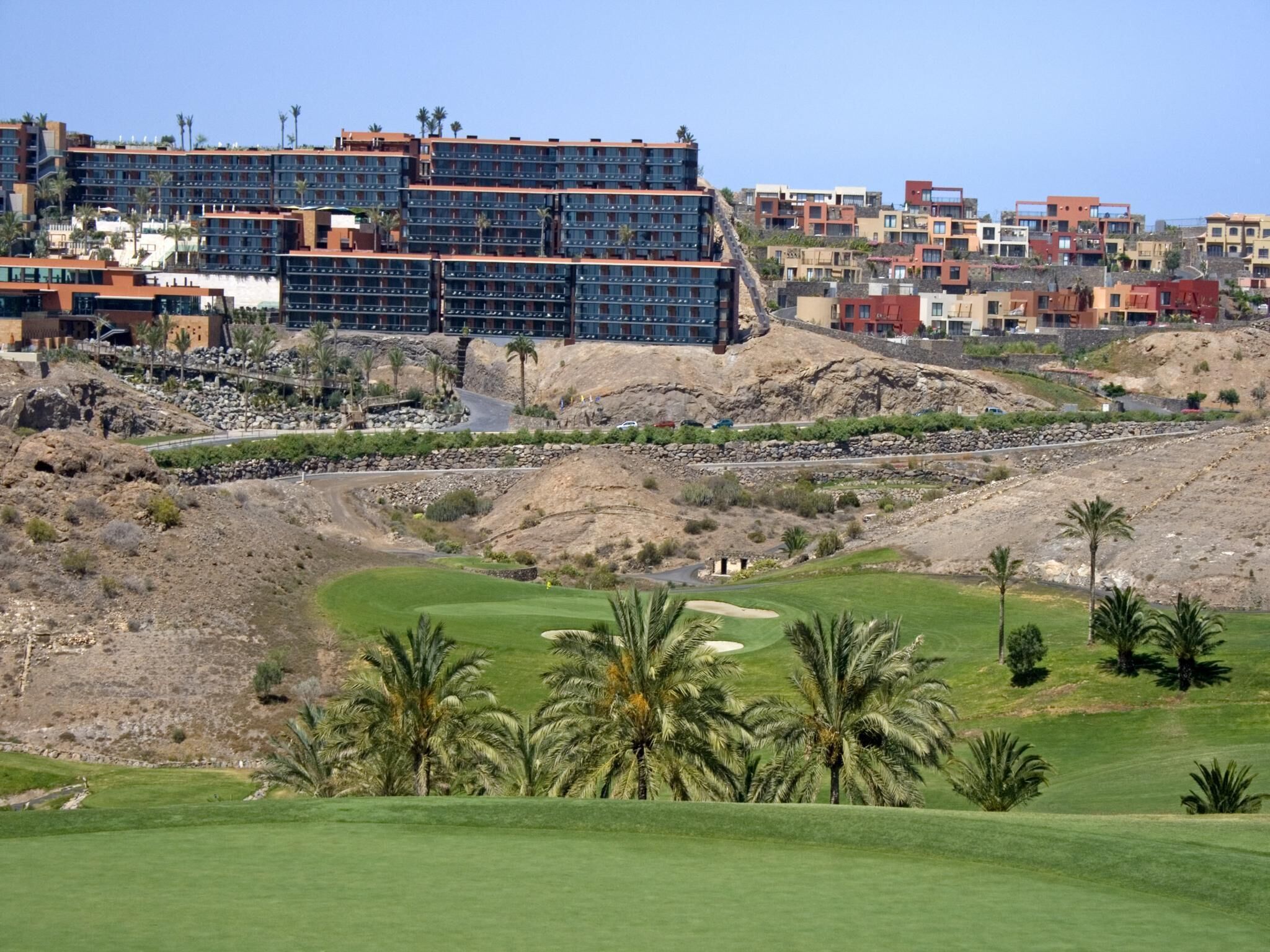 Un campo de golf con vistas a un complejo hotelero al fondo.