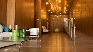 Ein modernes Interieur mit Holzwänden, einem Glastisch, einem weißen Sofa und einer Treppe mit Metallgeländern.