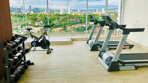 Ein Fitnessstudio mit Laufbändern und Hanteln, große Fenster mit Blick auf die Stadt.