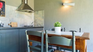 A modern kitchen with grey cabinets, a wooden dining table, and a stainless steel range hood. - Refined and welcoming Villa with private pool surrounded by nature (Omignano Scalo)