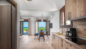 Een moderne keuken met uitzicht op zee, houten kastjes, een eethoek met stoelen en een tafel.