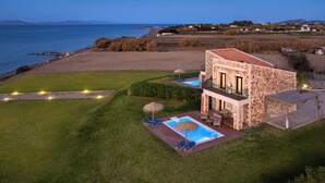 Een stenen villa met een zwembad, een balkon en uitzicht op zee.