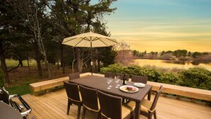An outdoor dining area with a table, chairs, and an umbrella. - Cape Cod Intellectual Property (Eastham)