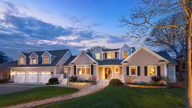 A two-story house with a front porch, a driveway, and a well-maintained lawn. - Cape Cod Intellectual Property (Eastham)