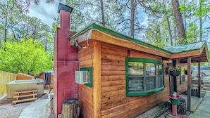 A wooden cabin with a chimney, a window with shutters, and a small porch area.