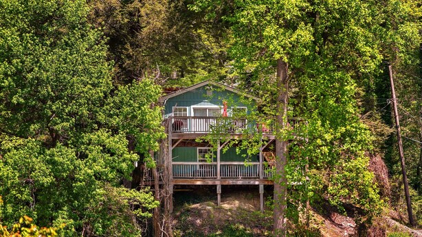 Eine zweistöckige Holzhütte, umgeben von dichtem Wald.