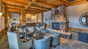 A cozy lounge area with leather chairs, a stone fireplace, and wooden beams on the ceiling. - Cozy Ski-In/Ski-Out Winter Park Resort Condo! (Winter Park)