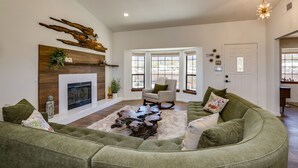 A spacious living room with a fireplace, a green sectional sofa, and a wooden coffee table. - New Roadrunner heights (Joshua Tree)