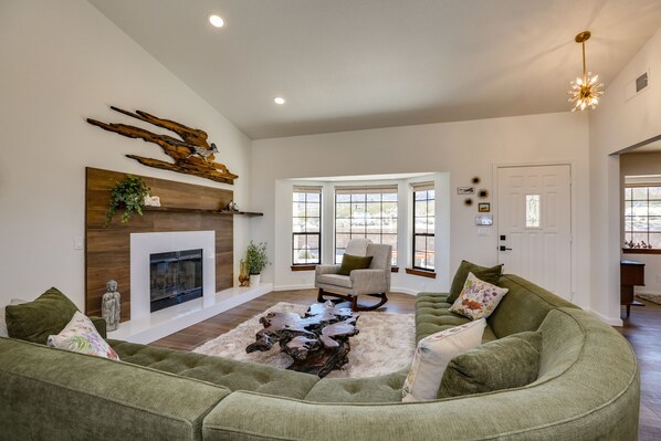 A spacious living room with a fireplace, a green sectional sofa, and a wooden coffee table.
