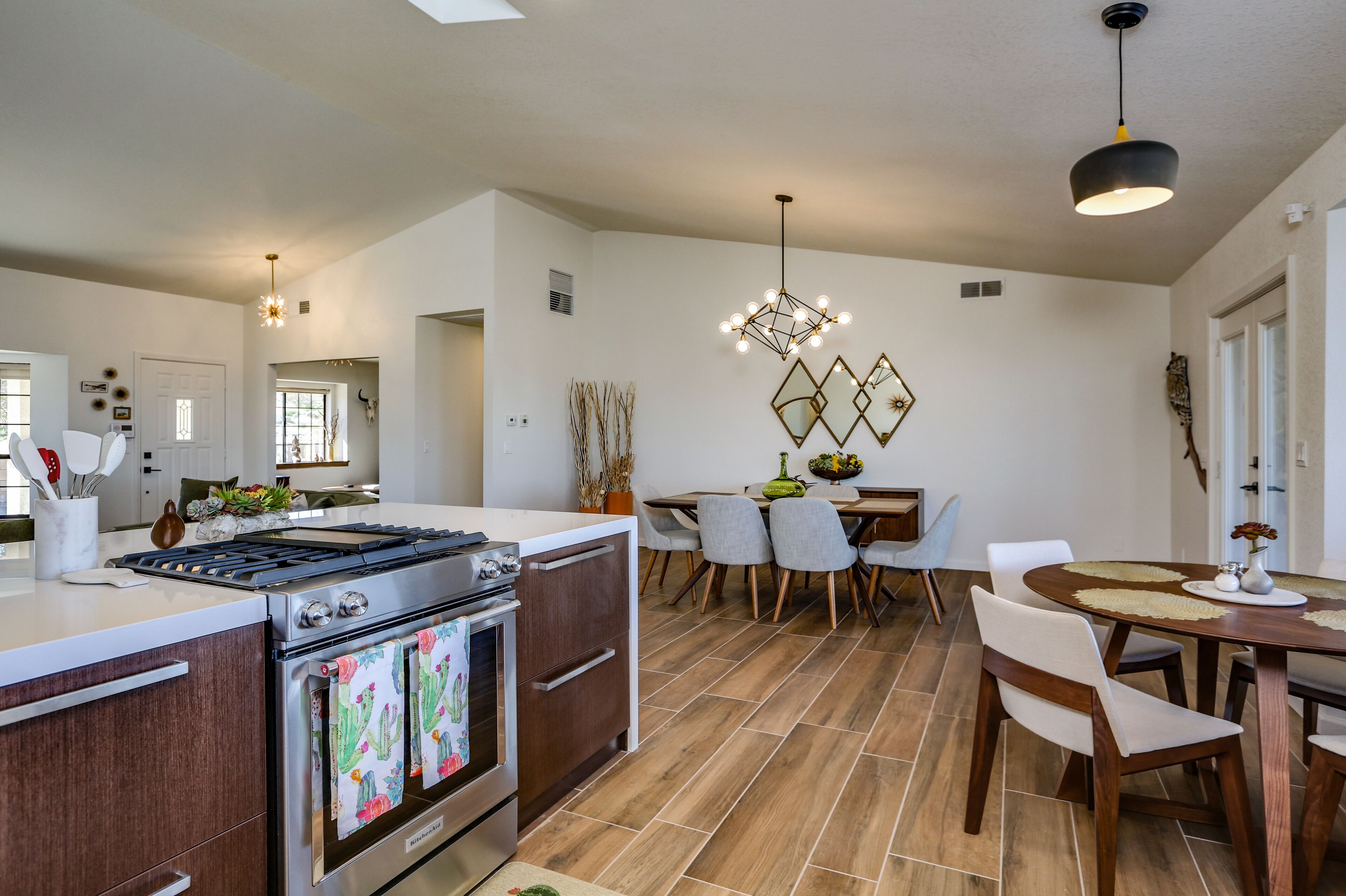 A modern kitchen with a gas stove, oven, and a dining area with a wooden table and chairs.