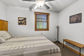 A bedroom with a bed, a ceiling fan, a window with blinds, a wall-mounted light fixture, and a poster. - Total Privacy, Plus fun: Hot tub, pool table (Rockbridge)