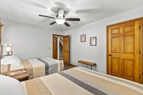 A bedroom with two beds, a ceiling fan, wooden doors, and framed pictures on the wall. - Total Privacy, Plus fun: Hot tub, pool table (Rockbridge)