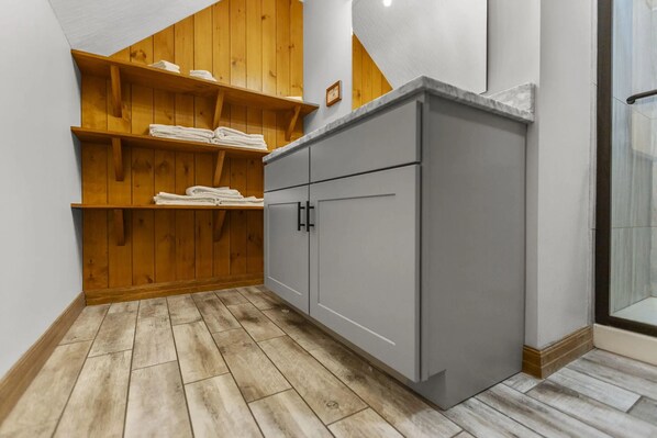 A corner bathroom with wooden shelves, grey cabinets, and a tiled floor. - Total Privacy, Plus fun: Hot tub, pool table (Rockbridge)