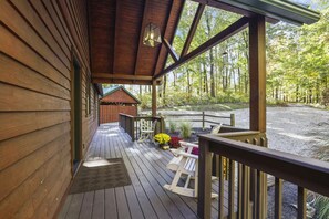 A wooden deck with a covered porch, a picnic table, and a view of a forested area. - Total Privacy, Plus fun: Hot tub, pool table (Rockbridge)
