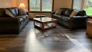A living room with two leather sofas, a glass-top coffee table, and a lamp. - The Pines of Apple Valley.  31 beautiful vacation cabins. (Howard)