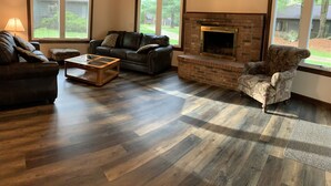A living room with a fireplace, a leather sofa, a patterned armchair, and a coffee table. - The Pines of Apple Valley.  31 beautiful vacation cabins. (Howard)