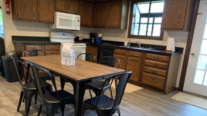 A kitchen with wooden cabinets, a microwave, a stove, and a dining table with chairs. - The Pines of Apple Valley.  31 beautiful vacation cabins. (Howard)