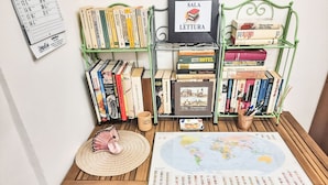 Un'area studio con scaffali, un globo, una mappa e un quadro incorniciato con la scritta 'SALA LETTURA'.
