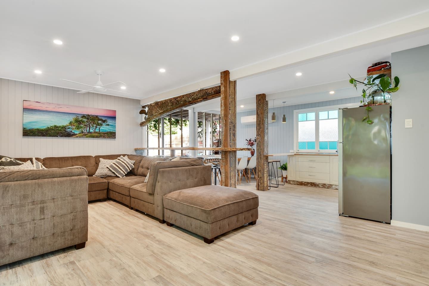 A spacious living area with a sectional sofa, a dining table, and a kitchen area with a refrigerator.