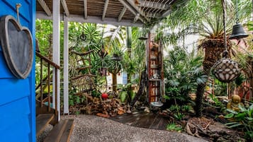 A tropical garden with a wooden staircase, hanging bells, and a variety of plants.
