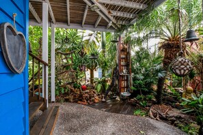 Un giardino tropicale con una scala di legno, campanelle appese e diverse piante.