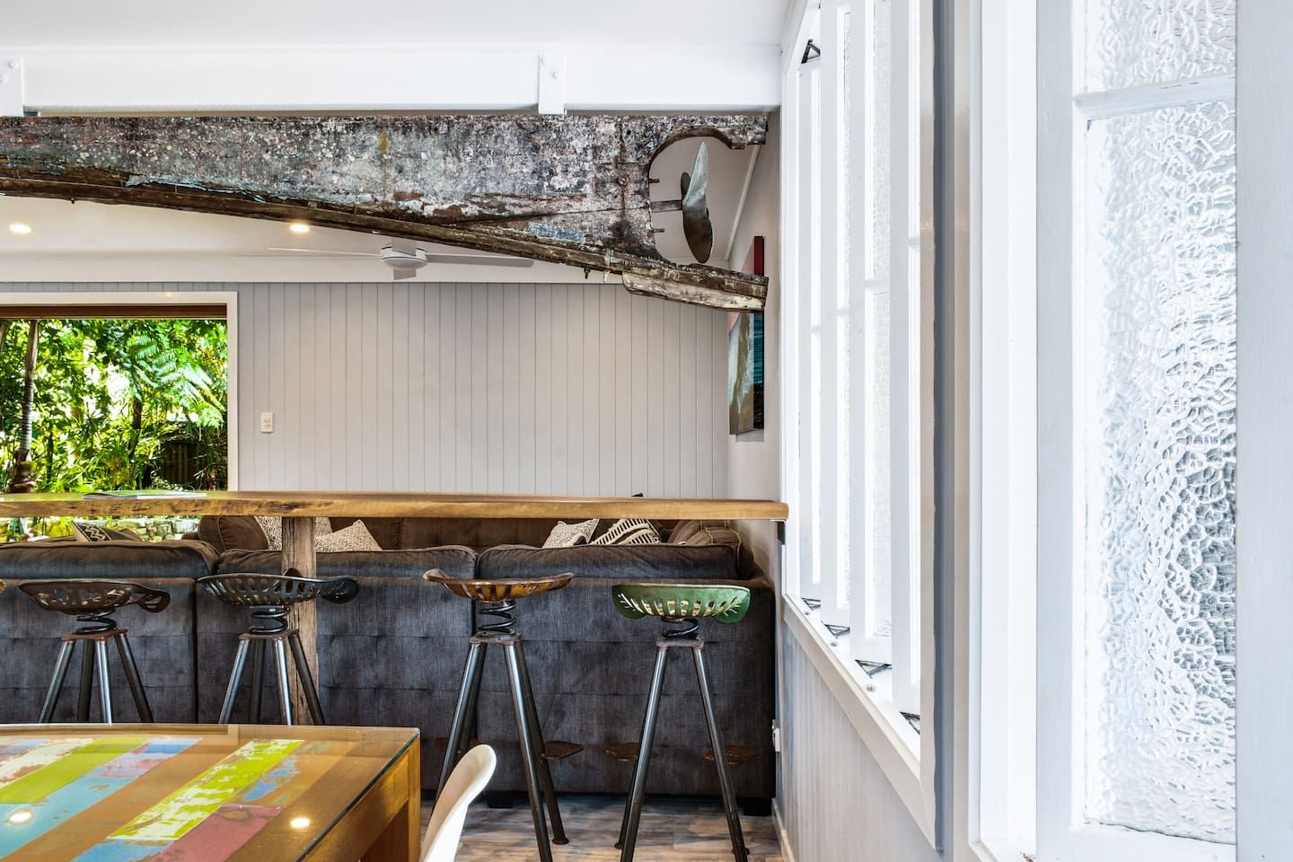 A bar area with a rustic ceiling, wooden bar counter, and stools.