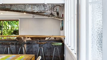 A bar area with a rustic ceiling, wooden bar counter, and stools.