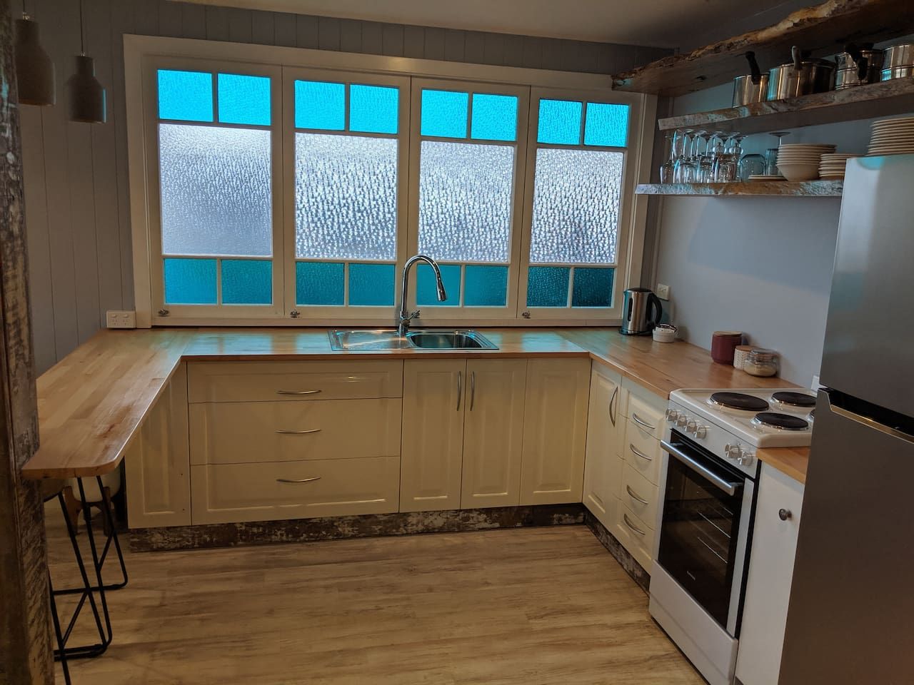 A kitchen with a wooden countertop, a sink, cabinets, a stove, and a refrigerator.